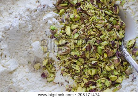 Preparation of pistachio cake from nuts and flour with a silver spoon.