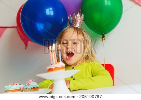 happy cute little girl make wish blow candles at birthday party