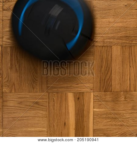 Top view of robotic vacuum cleaner on wooden parquet floor, natural movement, natural motion blur. image with square aspect ratio