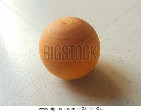 Wooden Sphere Resting on Marble Table Top