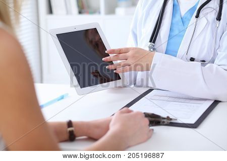 Close up of a doctor and  patient hands while phisician pointing into tablet computer monitor. Medicine and health care concept