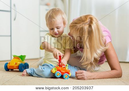 Cute child boy and mother repairing toy car at home