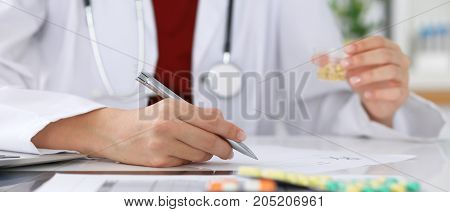 Female medicine doctor fills up prescription form to patient closeup. Panacea and life save, prescribe treatment, legal drug store, contraception concept.
