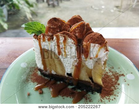 Banoffee pie on plate with bananas whipped cream coco powder