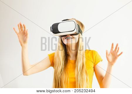 Young woman wearing virtual reality goggles headset vr box stretching arms. Connection technology new generation and progress concept. Studio shot on gray