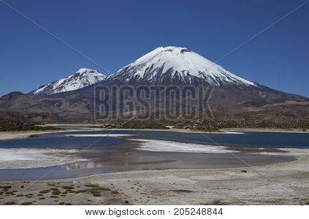 Volcanoes Parinacota and Pomerape in Lauca National Park high on the Altiplano of northern Chile. In the foreground lakes known as Lagunas de Cotacani