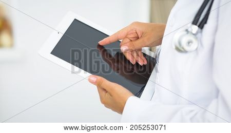 Woman doctor using tablet computer while standing straight in hospital.