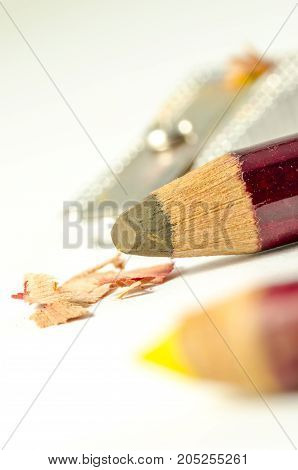 colored pencils sharpened with a pencil sharpner in the background. school.