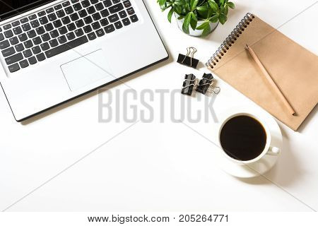 Office workplace with laptop, cup of coffee, sketch-book, accessories on white background. Top view with copy space.