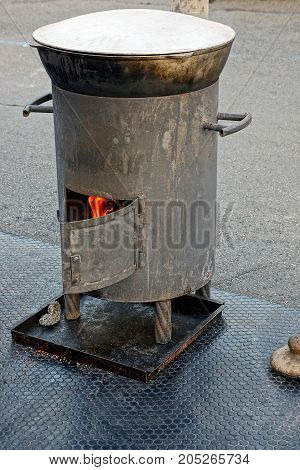 A boiler with a burning furnace and a closed pot in the street in the courtyard