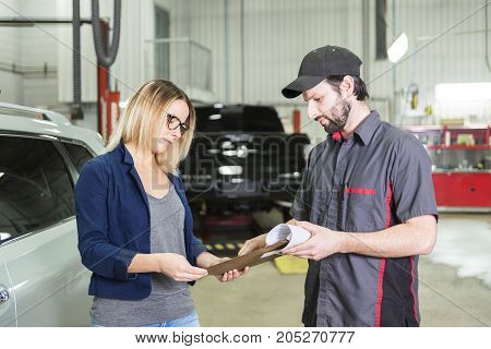 An auto mechanic and female customer in garage