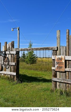 END SPEED ZONE sign in a pasture and fields divided by a weathered wooden fence and a barbed wire fence.