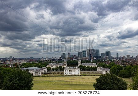 Epic stormy view of Canary Warf, Maritime Museum, Old Royal Naval College and London Skyline from Greenwich Park, London England.
