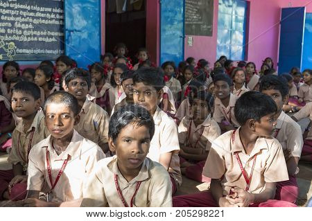 PONDICHERY PUDUCHERY INDIA - SEPTEMBER 04 2017. Outdoor meeting of the children of the school with uniforms sitting on the floor waiting for sport equipments as a gift from an association.