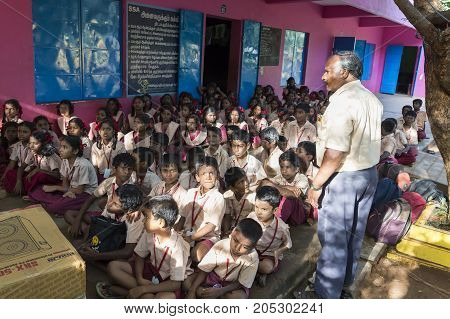 PONDICHERY PUDUCHERY INDIA - SEPTEMBER 04 2017. Outdoor meeting of the children of the school with uniforms sitting on the floor waiting for sport equipments as a gift from an association.