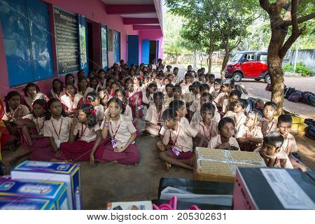 PONDICHERY PUDUCHERY INDIA - SEPTEMBER 04 2017. Outdoor meeting of the children of the school with uniforms sitting on the floor waiting for sport equipments as a gift from an association.
