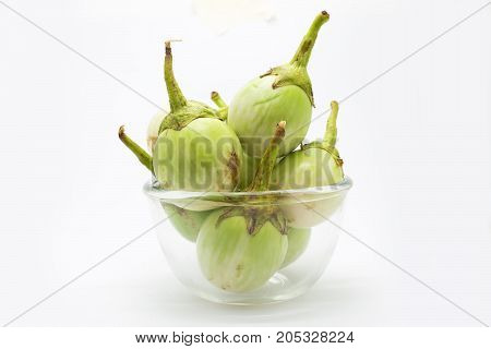 Green eggplant on glass bowl on white background