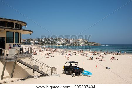 SYDNEY,NSW,AUSTRALIA-NOVEMBER 21,2016: Tourists at Bondi Beach with lifeguard tower and rescue vehicle in Sydney, Australia.