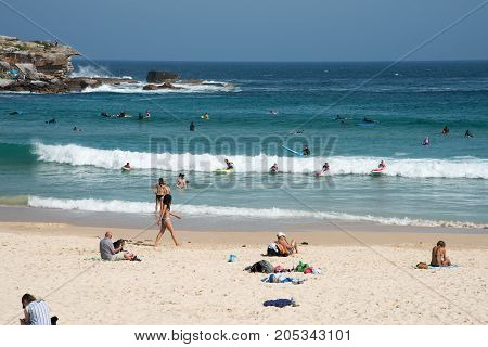 SYDNEY,NSW,AUSTRALIA-NOVEMBER 21,2016: Sandstone cliffs, surfers and beachgoers on the Pacific Ocean coast at Bondi Beach in Sydney, Australia.