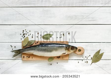 Herring with spices on a wooden board. The background. Rustic style, selective focus.