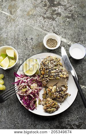 A healthy snack lunch. Baked chicken breast in breaded LSA pumpkin seeds, flax seeds, sunflower seeds, almonds for crispy appetizing crust with radicchio salad, green grapes with basil in a plate on the table. Top View