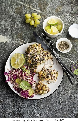 A healthy snack lunch. Baked chicken breast in breaded LSA pumpkin seeds, flax seeds, sunflower seeds, almonds for crispy appetizing crust with radicchio salad, green grapes with basil in a plate on the table. Top View