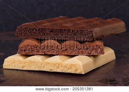 milk dark and white chocolate bars on grunge background