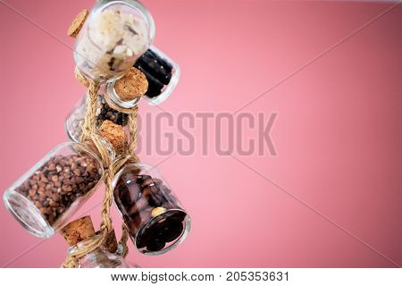 Quinoa, bulgur and couscous cereals. Vegetarian and dieting food concept. Cereals in glass jars are amused by a linen lace on is dusty a pink background
