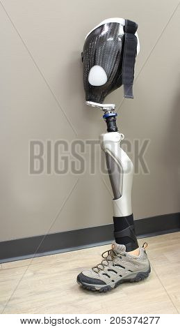 Leg prosthesis with shoe, leaning against a wall, vertical aspect