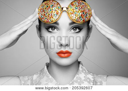 Portrait of beautiful young woman with colored glasses. Beauty fashion. Perfect make-up. Colorful decoration. Jewelry