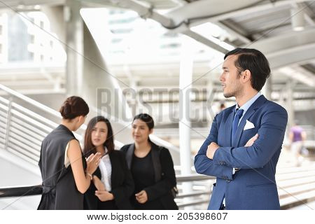 Portrait of confident Handsome Businessman standing with arms folded and looking at the camera with businesspeople background. Copy space.