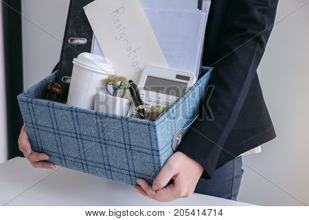 business woman carrying packing up all his personal belongings and files into a brown cardboard box to resignation in modern office resign concept.