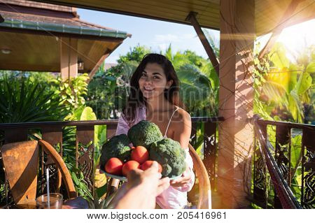 Male Hand Giving Beautiful Woman Plate Of Fresh Vegetables Pov Girl Happy Smiling Sit On Summer Terrace In Tropical Forest Organic Food And Nutrition Concept