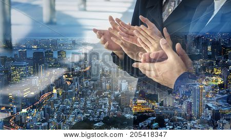 the posture clapping hand of people in business suite with overlay of modern nightcity