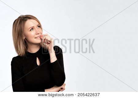Glamour fashion woman with long blonde hair and natural evening makeup wear black dress. Prepare for party. She looks up and thinks about future