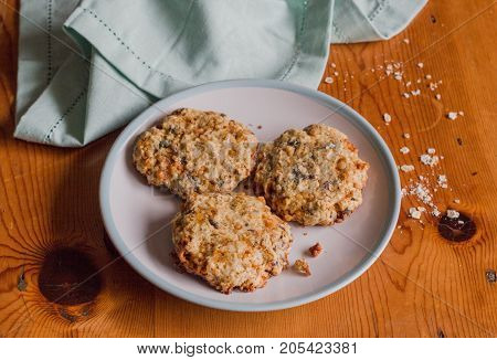 Homemade sweet and crunchy oat meal cookies on rustic bright wooden kitchen table with oats and blue cloth - Food background