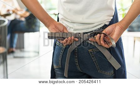 Woman tying up her apron around the waist