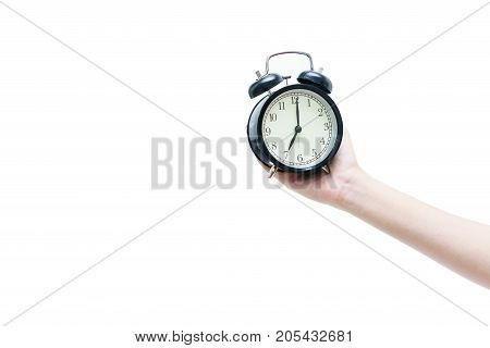 Woman's hand holding black traditional wind-up (keywound) mechanical spring-driven alarm clock isolated on white background