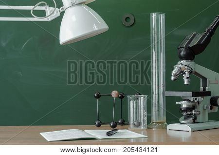 Teacher student biologist or chemist desk table. Education background. Education concept. Microscope vial flask beaker and book with pen and lamp on the table.