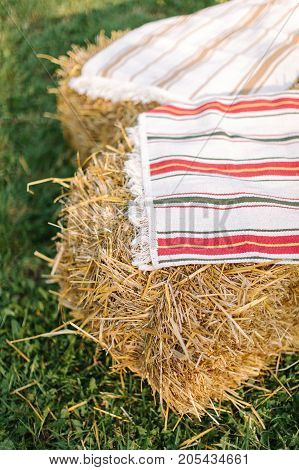 handmade, gardening, decoration concept. two small squares of dry grass covered with white homemade towels with red and green strips and with fringe on the edges
