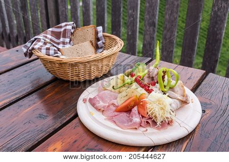 Traditional Brettljausn with bread and a lot of cold cuts on wooden table on south Styrian vine route in Austria