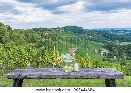 Jars with grapes and candle on wooden bench near vineyard along the south Styrian vine route in Austria Europe