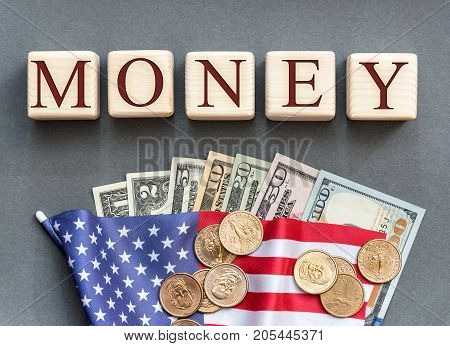 Word "MONEY" written by wooden cubes with american flag and american dollar bills.