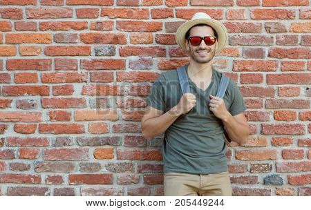 Outdoor Portrait Of Young Caucasian Man Pictured With Red Brick Wall In Background Looking Through S