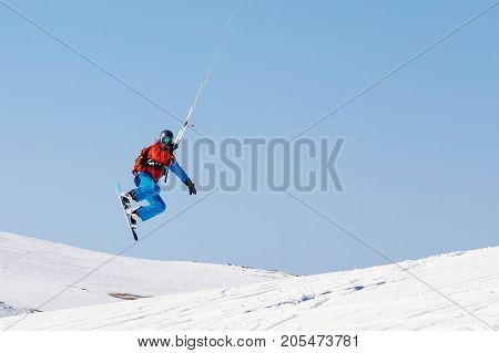 Snowboarder with a kite on fresh snow in the winter in the tundra of Russia against a clear blue sky. Teriberka, Kola Peninsula, Russia. Concept of winter sports snowkite.