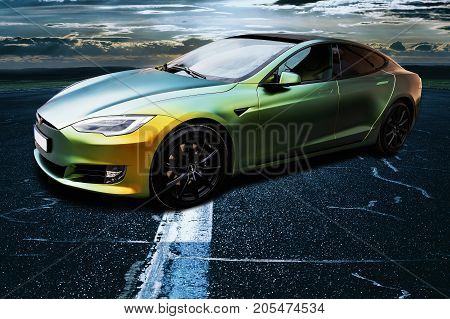 PRAGUE CZECH REPUBLIC - SEPTEMBER 23 2017. Tesla Model S gold and green color on airport runway in the evening. Tesla car.