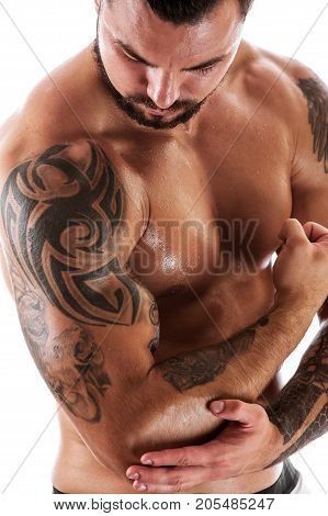 Muscular sexy fitness model posing shirtless over white background. Portrait of Athletic young man with tattooed torso.
