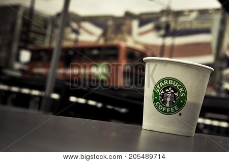LONDON, UK - OCTOBER 13, 2009 - A Starbucks paper coffee cup on a table in Camden Town, London bus and Union Jack on background.