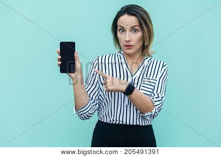 Amazed Blonde Business Woman Pointing Finger At Smart Phone And Looking At Camera With Shoked Face.