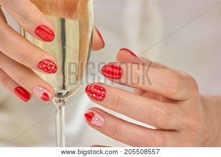 Glass of champagne in manicured female hands. Lady hands with beautiful winter manicure holding glass of champagne.